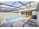 Inviting outdoor pool area featuring a covered patio, grill, lounge chairs, and a serene view of the property at 7487 Oakmoss Loop, Davenport, FL 33837
