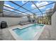 Private pool area boasts brick pavers, a covered patio, outdoor seating, grill, and lush landscaping at 7487 Oakmoss Loop, Davenport, FL 33837