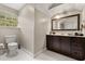 Well-lit bathroom with dark wooden vanity, a toilet and white tile floors with natural light at 8800 Torey Pines Ter, Orlando, FL 32819