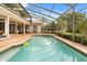 Backyard oasis with screened pool, brick patio, and lush landscaping, perfect for outdoor living at 8800 Torey Pines Ter, Orlando, FL 32819