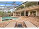 Spacious backyard with a screened pool, hot tub, brick patio, and multiple seating areas for entertaining at 8800 Torey Pines Ter, Orlando, FL 32819