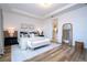 Spacious bedroom with tray ceiling, wood floors, and a view into the ensuite bathroom at 9224 Legado Dr, Windermere, FL 34786