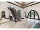 Stunning foyer with wrought iron staircase, archway, and travertine tile flooring illuminated by a dazzling chandelier at 10138 Enchanted Oak Dr, Golden Oak, FL 32836