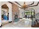 Grand foyer featuring a brick fireplace, elegant chandelier, travertine floors, and staircase with wrought iron railings at 10138 Enchanted Oak Dr, Golden Oak, FL 32836