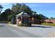 View of the gated entrance with brick guard house and a brick-paved road leading into the community at 10662 Woodchase Cir, Orlando, FL 32836