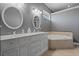 A stylish main bathroom has dual vanities, a soaking tub, and neutral-toned tile at 10662 Woodchase Cir, Orlando, FL 32836