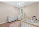 Charming Bedroom featuring a white crib, dresser, and rocking chair, creating a cozy and inviting space at 1125 E Tuskawilla Pt, Winter Springs, FL 32708