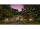 Charming single-story home with lush landscaping, arched entry, and a beautifully lit facade at dusk at 1125 E Tuskawilla Pt, Winter Springs, FL 32708