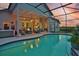 Twilight view of the screened pool and patio area featuring a hot tub and ample seating at 1137 Palm Cove Dr, Orlando, FL 32835