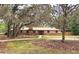 Charming home with mature trees, brick accents, a well-manicured lawn, and a circular driveway at 1212 Foxfire Dr, Apopka, FL 32712