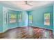 Well lit bedroom featuring blue walls, hardwood floors, and three windows overlooking trees at 1406 Cr 542G, Bushnell, FL 33513
