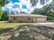 A tan stucco single-story home featuring a spacious two-car garage on a lush green lot at 1406 Cr 542G, Bushnell, FL 33513