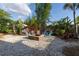 Relaxing backyard features a stylish stone fire pit surrounded by colorful Adirondack chairs and lush plants at 15714 Turkey Farm Rd, Minneola, FL 34715