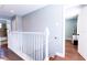 Upstairs hallway with wood floors, white railing, and doorways leading to rooms at 15714 Turkey Farm Rd, Minneola, FL 34715