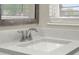 Bright bathroom sink featuring a stainless steel faucet, textured countertop, and decorative mirror with natural lighting at 1805 Knox Ave, Sanford, FL 32771