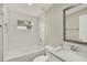 All-white bathroom features vanity with solid surface counters, tub-shower combo with window, and decorative mirror at 1805 Knox Ave, Sanford, FL 32771