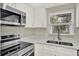Bright kitchen features stainless steel appliances, white cabinetry and counters, and double bowl sink below a window at 1805 Knox Ave, Sanford, FL 32771