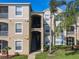 Well-maintained condo building with tan exterior, palm trees, and visible unit numbers for easy identification at 2300 Silver Palm Dr # 205, Kissimmee, FL 34747