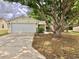 Inviting single-story home with a large tree in the front yard and a white two-car garage at 307 Santa Clara Cir, Lady Lake, FL 32159
