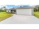 Single-story home featuring an attached two-car garage and freshly poured concrete driveway at 315 Fisher Rd, Ocklawaha, FL 32179