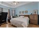 Bright main bedroom with light blue walls, wood floors, king bed, treadmill, and cozy armchair at 3416 Gerber Daisy Ln, Oviedo, FL 32766