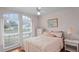 Cozy bedroom featuring a light pink comforter set, a large arched window, and hardwood floors at 3617 Cherry Hill Dr, Orlando, FL 32822