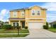 Inviting two-story home featuring a well-manicured lawn, lush landscaping, and an attached two-car garage at 3808 Enchantment Ln, St Cloud, FL 34772