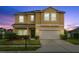 Inviting two-story home featuring a well-manicured lawn, lush landscaping, and an attached two-car garage at 3808 Enchantment Ln, St Cloud, FL 34772