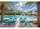 Large community pool with lounge chairs and umbrellas and view of splashpad at 4420 Shiva Loop, Kissimmee, FL 34746