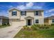 Two-story home featuring a two car garage, light yellow siding, dark shutters, and a well maintained lawn at 4423 Blackbird St, Kissimmee, FL 34746
