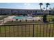 View of the community pool surrounded by a fence, greenery, and building in the background at 5505 Hernandes Dr # 118, Orlando, FL 32808