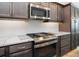 Modern kitchen featuring granite countertops, stainless steel appliances, and dark wood cabinets at 5896 Barclay Ct, The Villages, FL 32163