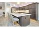 Bright kitchen features gray cabinets, stainless appliances, island, and wood flooring at 5896 Barclay Ct, The Villages, FL 32163