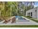 Inviting pool area with lounge chairs in landscaped backyard with tropical plants and trees at 613 Daniels Ave, Orlando, FL 32801