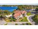Beautiful building featuring a red tile roof, manicured landscaping, and a scenic lake view, surrounded by lush trees at 6301 Parson Brown Dr, Orlando, FL 32819