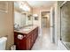 Bathroom with double sink vanity, and hallway leading to other rooms and a shower with tiled walls at 677 Cheoy Lee Cir, Winter Springs, FL 32708