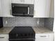 Close-up of kitchen with stainless steel microwave, modern backsplash, and granite countertops at 101 Dovetail Ct, Apopka, FL 32703