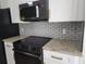 Modern kitchen features stainless steel appliances, granite countertops, and a stylish backsplash at 101 Dovetail Ct, Apopka, FL 32703