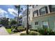 Attractive condo building with tropical landscaping, mature palms, and colorful facade at 11446 Jasper Kay Terrace # 202, Windermere, FL 34786