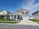 Attractive two-story home boasts a gray exterior, covered front porch, manicured lawn, and a driveway leading to a garage at 1803 Perch Hammock Loop, Groveland, FL 34736