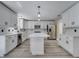 Bright kitchen with gray wood-look floors, white cabinets, an island with pendant lights, and stainless steel appliances at 2004 Prescott Blvd, Deltona, FL 32738