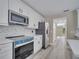 Bright kitchen with gray wood-look floors, white cabinets, quartz countertops, and stainless steel appliances at 2004 Prescott Blvd, Deltona, FL 32738
