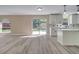 Open-concept kitchen with gray vinyl floors, granite countertops, and a sliding glass door to the backyard at 2004 Prescott Blvd, Deltona, FL 32738