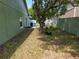 Backyard with tree and side of house with window and an unkept lawn covered in leaves at 209 Silas Phelps W Ct, Orlando, FL 32828