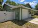 Side view of a home featuring a white garage door and a white privacy fence, partially shaded by the trees at 209 Silas Phelps W Ct, Orlando, FL 32828