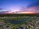 Sunset aerial view of a well-maintained community with a lake and manicured lawns at 3348 Perennial Ln, Kissimmee, FL 34746