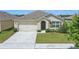 Well-maintained single-story home with a two-car garage and green lawn at 3348 Perennial Ln, Kissimmee, FL 34746