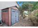 A well-maintained backyard shed with access to the yard via a wooden arbor, surrounded by mature trees and plants at 4353 Steed Ter, Winter Park, FL 32792