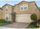 Two-story home featuring a two-car garage and neutral stucco exterior with well-maintained landscaping at 8828 Bengal Ct, Kissimmee, FL 34747