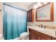 Cozy bathroom featuring warm toned vanity with granite counter, framed mirror, and shower with blue-toned curtain at 1052 Dees Dr, Oviedo, FL 32765